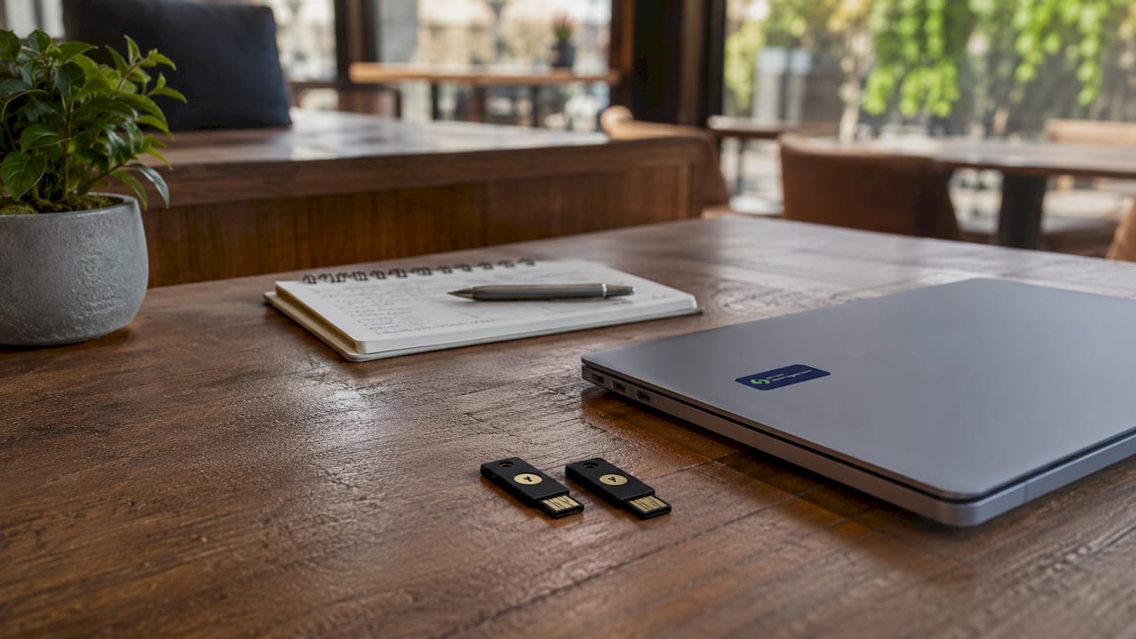 1783908892648_Close-up-of-YubiKeys-and-laptop-on-tech-desk Μια κοντινή λήψη με YubiKeys και laptop πάνω σε ένα γραφείο γεμάτο τεχνολογικά gadgets.
